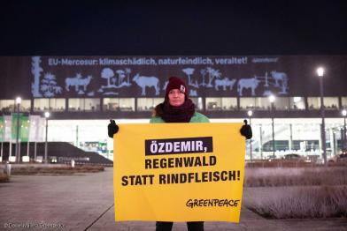 Aktivistin hält Banner vor dem CityCube Berlin 