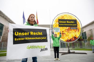 Eine Jugendliche hällt ein Banner: Unser Recht: Echter Klimaschutz jetzt!