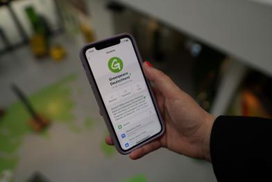 Hand hält Smartphone mit Greenpeace-Whatsapp-Gruppe
