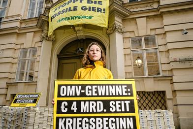 Vor Finanzministerium in Wien: Aktivistin hält Schild "OMV-Gewinne: € 4 Milliarden seit Kriegsbeginn"