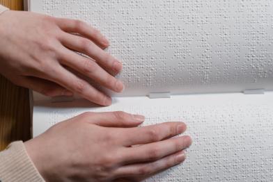 Zwei Hände, die Blindenschrift (Braille) ertasten 