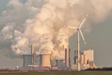 Windrad vor dem qualmenden Kohlekraftwerk Neurath