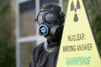 Greenpeace-Aktivist mit Gasmaske und Protestschild "Nuclear Power: Wrong Answer"