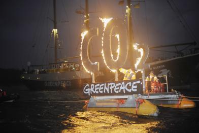 Brennendes CO2-Zeichen auf einem Greenpeace-Schlauchboot.