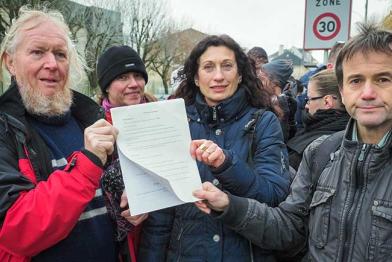 Bürger halten eine Strafanzeige u. a. gegen den Atomkonzern EDF vor der Polizeistation in Thionville hoch - wegen Gefährdung Dritter.