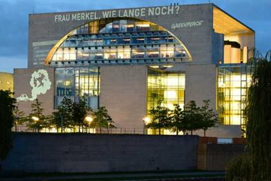 Projektion an das Bundeskanzleramt: „Frau Merkel, wie lange noch?“ und eine in Autoabgase gehüllte Erdkugel
