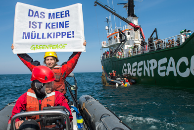 Greenpeace-Aktivisten protestieren im Sylter Außenriff, Nordsee, gegen die Verschmutzung der Meere. Hinter ihnen die Arctic Sunrise