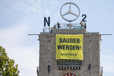 Auf dem Uhrturm des Stuttgarter Hauptbahnhofs machten Greenpeace-Aktivisten aus dem Mercedes-Stern ein NO2-Zeichen; auf ihrem Banner steht "Sauber werden!".