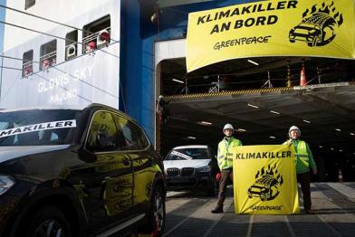 Auch auf der Laderampe stehen Aktivisten und Aktivistinnen mit Klimakiller-Handbannern