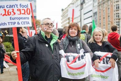 Ein Mann und zwei Frauen von Greenpeace stehen in Brüssel vor der Europäischen Kommission. Der Herr hält ein Schild in der Hand mit der Aufschrift: „You can’t fool 3.263.920 Europeans with TTIP & CETA“.
