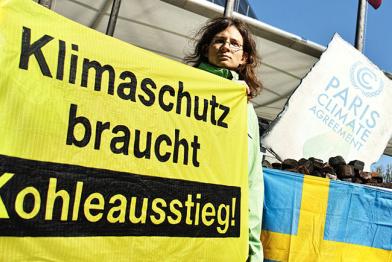 Aktivistin mit Banner "Klimaschutz braucht Kohleausstieg" vor der schweidischen Botschaft in Berlin