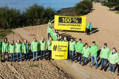 Zum Windrad formierte Greenpeace-Aktivisten stehen an der Elbe in Hamburg. 