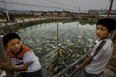 Zwei Jungen stehen vor einem stark verschmutzten Teich in Gurao, Shantou. In Gurao, wo sich die Wirtschaft auf die Textilproduktion konzentriert, hat Greenpeace ein hohes Maß an industrieller Verschmutzung festgestellt und die Auswirkungen auf die Gemeinde dokumentiert.