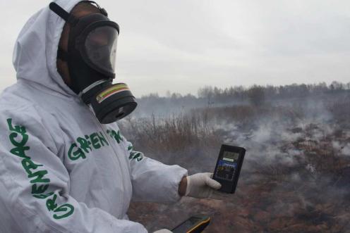 Ein Greenpeace-Mitglied in Schutzkleidung hält einen Geigerzähler in von Tschornobyl radioaktiv verseuchter Region
