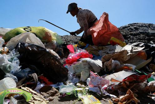 Eine ältere Müllsammlerin durchwühlt den Abfall auf einer Mülldeponie in Dumaguete City, Philippinen.