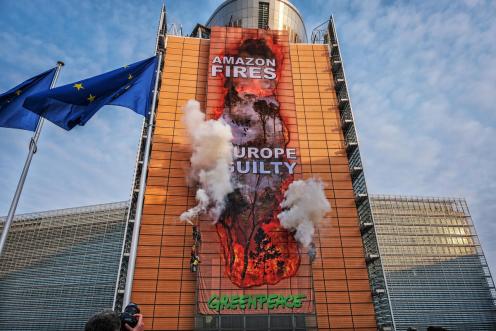 Aktivist:innen hängen riesiges Bild von Feuern im Amazonas an die Fassade der EU-Kommission