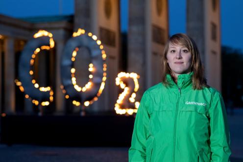 Greenpeace Klimaexpertin Lisa Göldner vor brennendem CO2-Zeichen