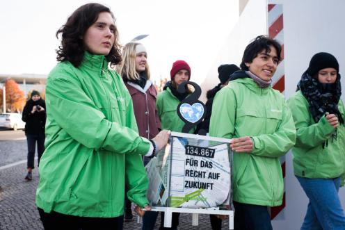 Jugendliche Aktivistinnen tragen die gesammelten Unterschriften einer Petition zur Unterstuetzung der Klimaklage