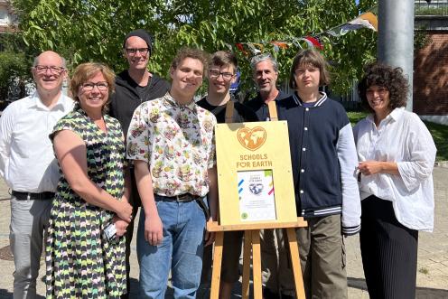 Schullabel steht auf Leinwand, dahinter eine Gruppe aus Lehrkräften, Schülern und Greenpeace-Mitarbeitenden