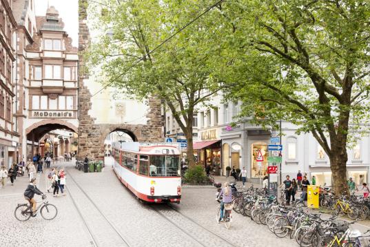 Verkehrs- und Wohninfrastruktur in Freiburg. Öffentliche Verkehrsmittel mit der Straßenbahn. Radfahrer:innen in der Stadt.
