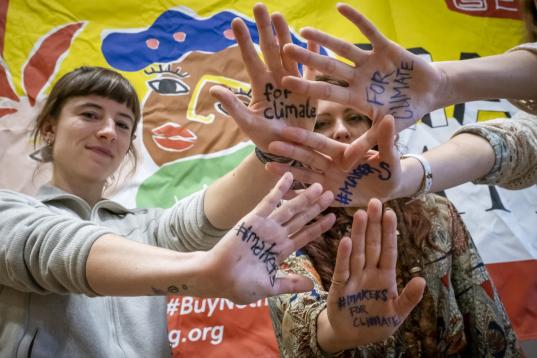 Greenpeace Aktive halten beim Make Something Day in Berlin Hände mit "Ressourcenschutz fürs Klima" hoch