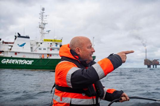 Greenpeace-Meeresexperte Christian Bussau in Rettungsweste auf dem Meer vor Greenepace-Schiff Esperanza