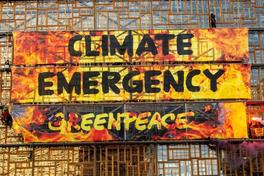 Flammenbanner mit "Climate Crisis" an Fassade von EU-Gebäude in Brüssel