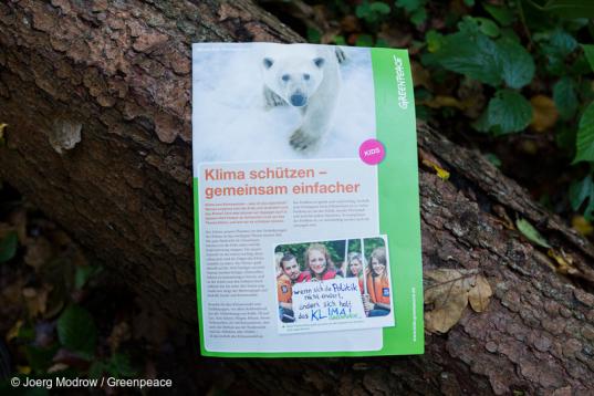 Greenpeace Kinderinfo "Klima schützen -gemeinsam einfacher", ausgelegt auf einem Baumstamm