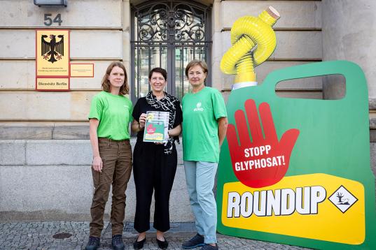 Christiane Huxdorff, Staatssekretärin Silvia Bender und Corinna Hölzel vom BUND neben einem überdimensionierten Glyphosat-Kanister.