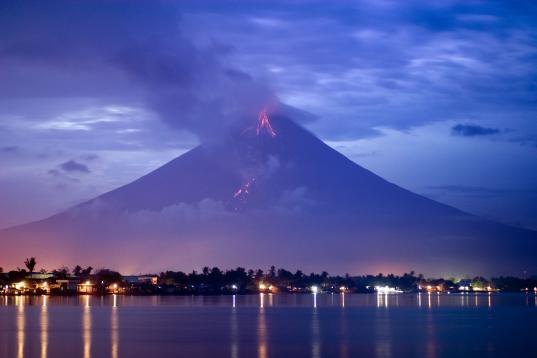 2006: Der philippinische Vulkan Mayon bricht aus. Rauch und Asche gehen über der Stadt Legazpi nieder.