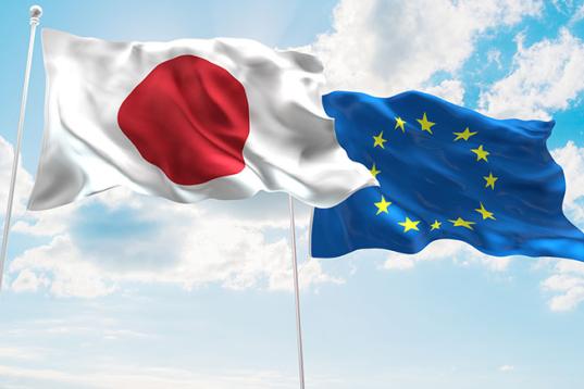 Zwei Flaggen, Japan und EU, vor blauem Himmel
