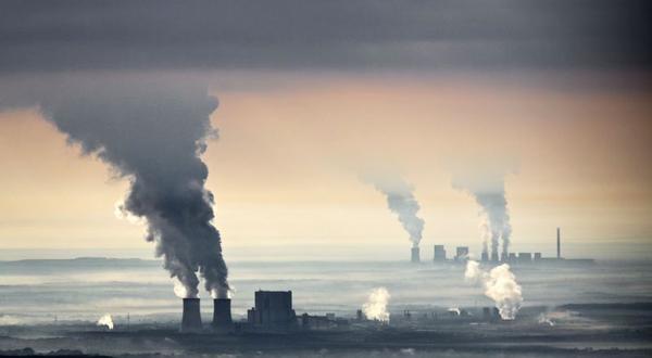 Das Braunkohlerevier in der Lausitz aus der Vogelperspektive, und umgeben von Qualm, der aus den Schornsteinen der Braunkohlekraftwerke kommt. 
