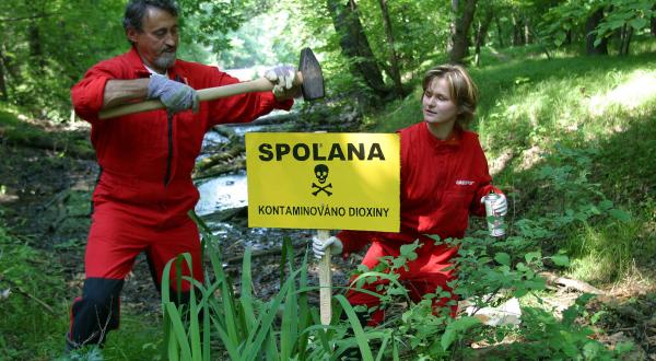Zwei Aktivist:innen platzieren ein Dioxin-Warnschild in einem Naturschutzgebiet neben der Chemiefabrik Spolana Neratovice, die stark mit Dioxinen verseucht ist.