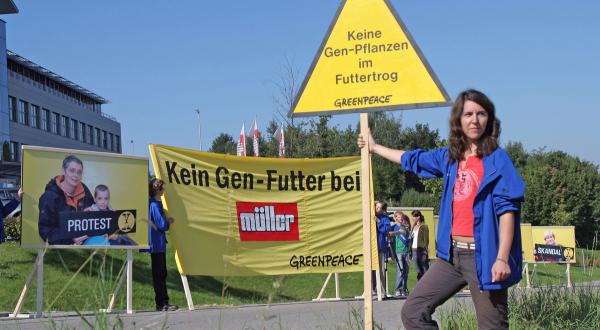 Aktive protestieren mit Banner vor der Firmenzentrale  der Molkerei Müller