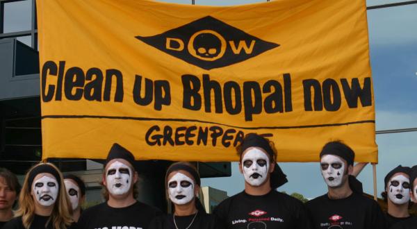 Freiwillige von Greenpeace vor einem Banner fordern Dow Chemicals auf, den Ort des weltweit schlimmsten Industrieunfalls in Bhopal in Indien aufzuräumen. 