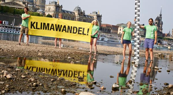 Greenpeace Aktivist:innen zeigen ein Banner mit der Aufschrift "Klimawandel!" im Flussbett der Elbe bei Dresden. Aufgrund einer langen Dürre ist der Wasserstand der Elbe nur noch ein Viertel so hoch wie normal.