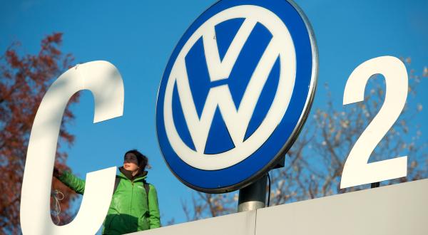 Greenpeace-Aktivist:innen protestieren während einer VW-Vorstandssitzung in Wolfsburg gegen Autoabgase am VW-Werkstor. Die Aktivist:innen verwandeln das VW-Logo in ein CO2-Zeichen. 
