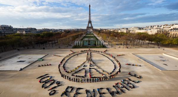 Hunderte Menschen bilden visuelle Klimaschutzbotschaft am Eiffelturm in Paris