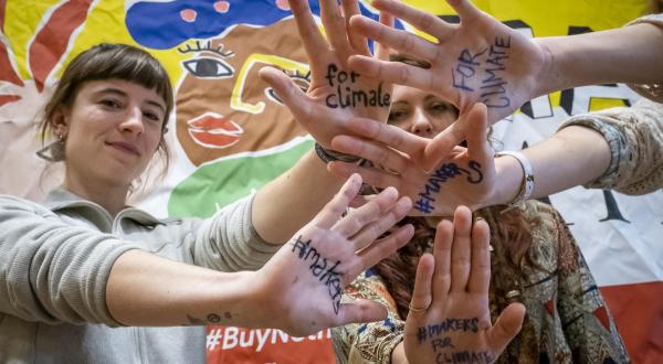 Greenpeace Aktive halten beim Make Something Day in Berlin Hände mit "Ressourcenschutz fürs Klima" hoch