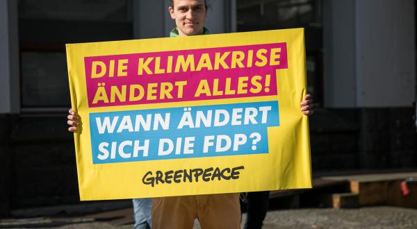 Mann mit Protestplakat "Die Klimakrise ändert alles, wann ändert sich die FDP?"