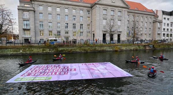 Greenpeace-Aktive protestieren mit Kajaks und einem Schwimmbanner vor dem Verteidigungsministerium