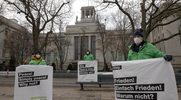 Greenpeace Aktivist:innen protestieren vor drei Botschaften in Berlin für Frieden in der Ukraine. Auf den Bannern steht in drei verschiedenen Sprachen, Englisch, Russisch und Deutsch: "Frieden! Einfach Frieden! Warum nicht?"