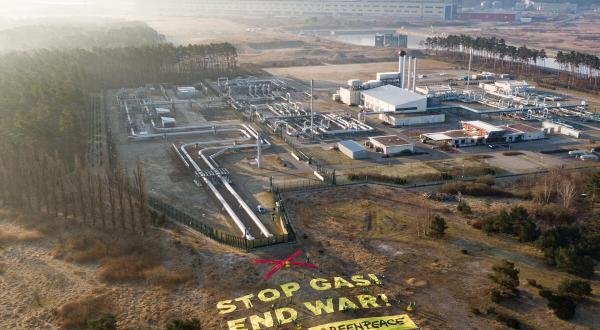 Greenpeace-Aktivist:innen protestieren an der Ostseepipeline Nord Stream 1 in Lubmin. Auf einem großen Transparent fordern sie: "Stop Gas! Krieg beenden!". 
