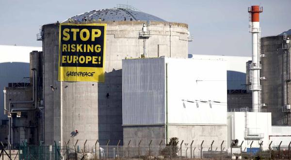 AKW Fessenheim mit Tank für abgebrannte Brennelemente und Greenpeace-Banner am Dach des Reaktors