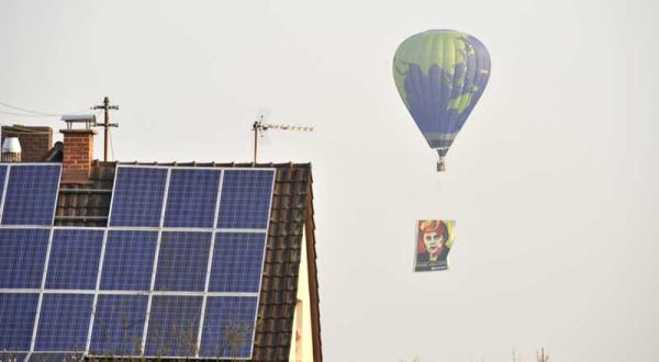 Heißluftballon mit Angela Merkel Banner fliegt an Haus mit Solaranlage vorbei, April 2009