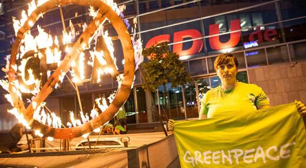 Greenpeace-Aktivisten protestieren mit einem drei Meter hohen glühenden CETA-Symbol vor der CDU-Parteizentrale in Berlin gegen CETA. "Frau Merkel, CETA schadet Umwelt und Demokratie!" sowie "CETA - Brandgefährlich!" stehen auf zwei Bannnern