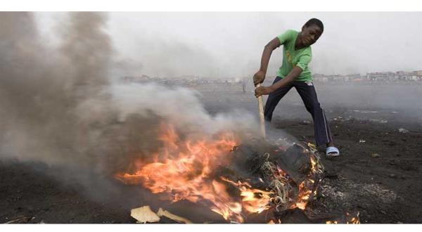Ein Kind versucht an einem Feuer u. a. Elektrokabel zu schmelzen, um an Kupfer zu gelangen, Ghana, November 2008.