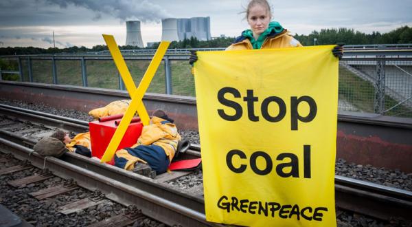 Ein Foto des vergangenen Protests. Aktivisten ketten sich an Gleisen um auf die Klimazerstörung aufmerksam machen, die der schmutzige Energieträger verursacht. 