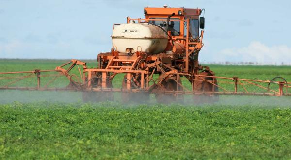 Traktor besprüht Soja-Feld in Brasilien mit Pestiziden