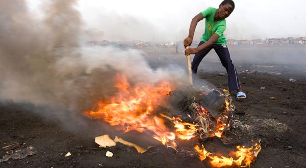 Ein Junge in Ghana beim Verbrennen von elektronischen Teilen